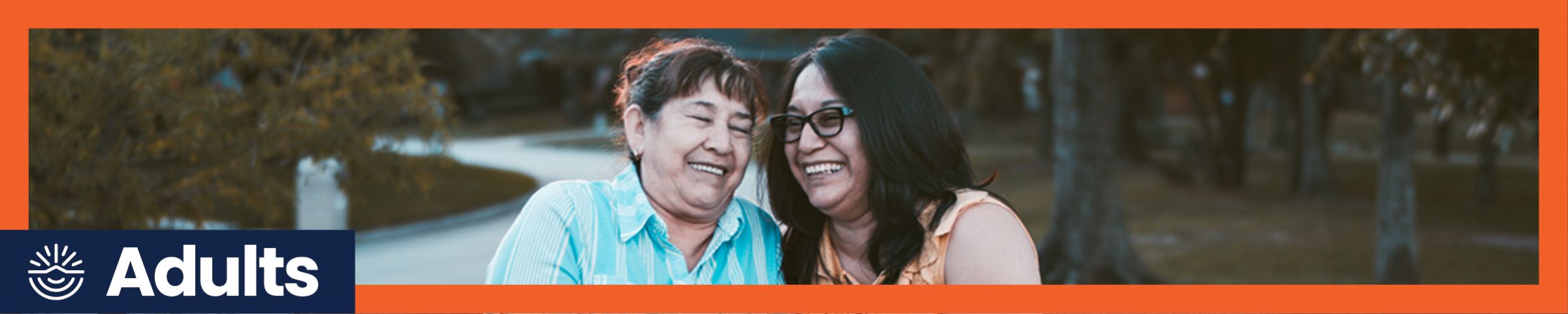 Two women chatting on bench outdoors in orange frame with "Adults" label