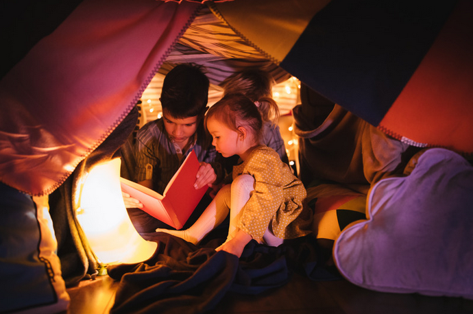 two children reading in a makeshift living room fort